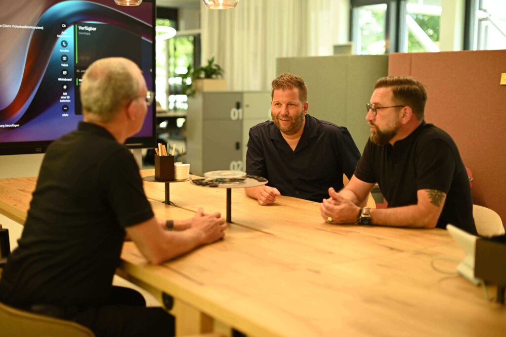 Tom, Matthias, Bruno sitting at a table discussing Bucher + Suter, Cisco, and Salesforce